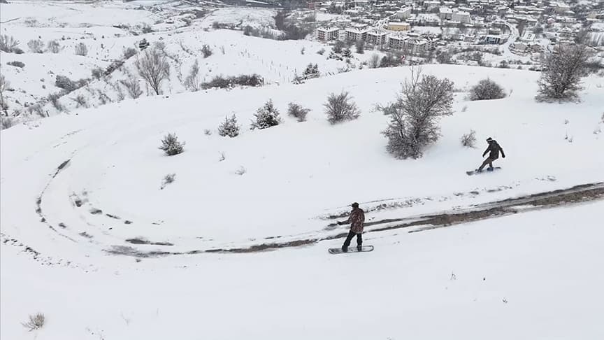 Erzincan'ın tarihi Kemah ilçesinde snowboardcular dağdan ilçe merkezine kayarak indi